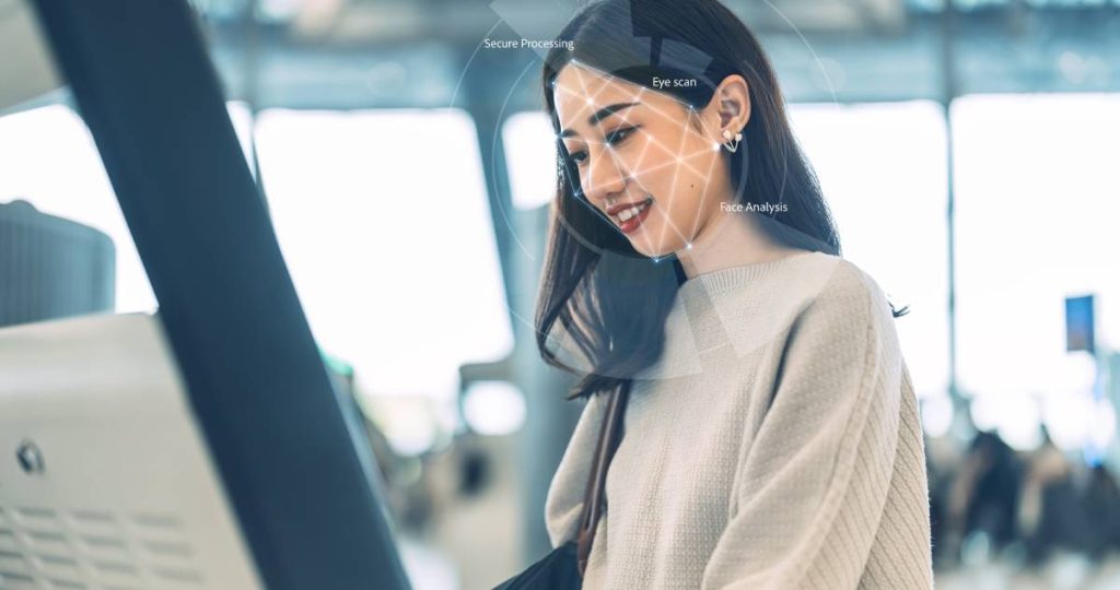 Viajera verificando su identidad mediante reconocimiento facial en un quiosco de aeropuerto