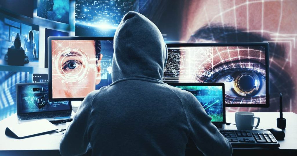 Hacker frente a monitores con escaneo biométrico