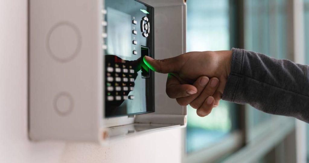 Una persona coloca su dedo en un lector de huellas dactilares montado en la pared para registrar su acceso