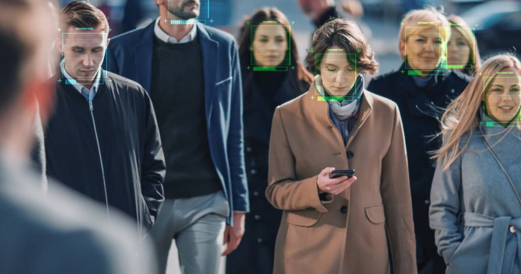 Un grupo de personas caminando por la calle con marcos digitales de reconocimiento facial sobre sus rostros
