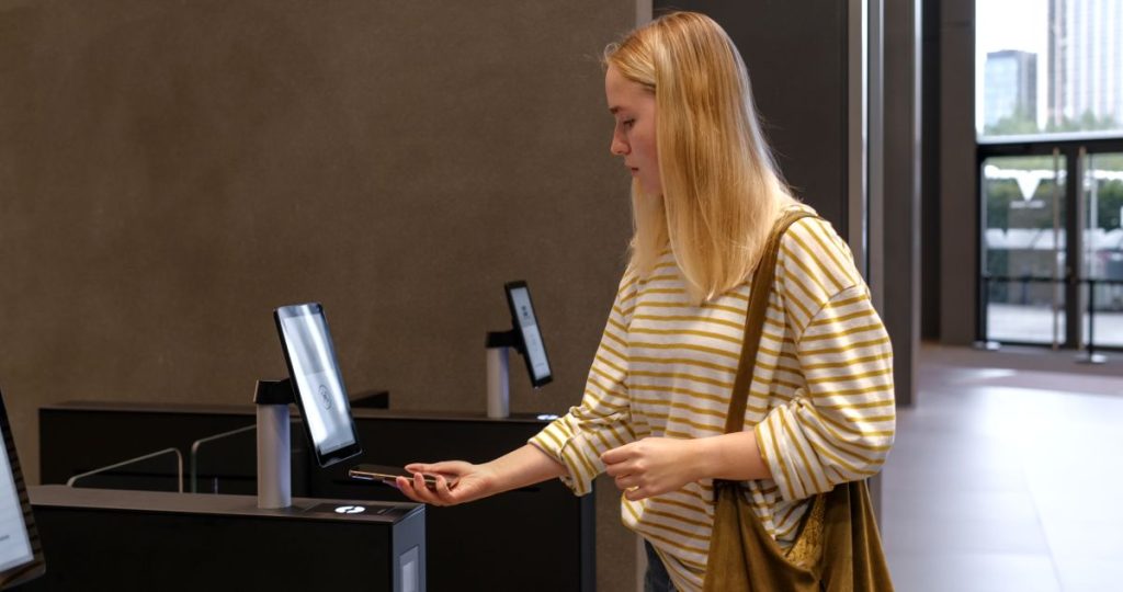 Una mujer utiliza su teléfono móvil para escanear y verificar su identidad digital en un terminal de acceso electrónico