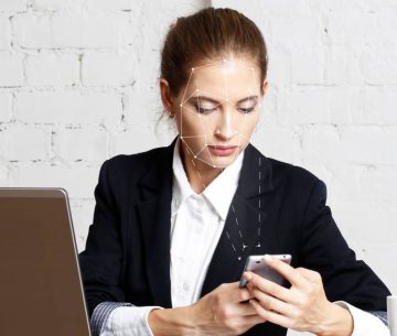 Una mujer en su oficina utiliza su teléfono móvil con una rejilla de reconocimiento facial sobre su rostro